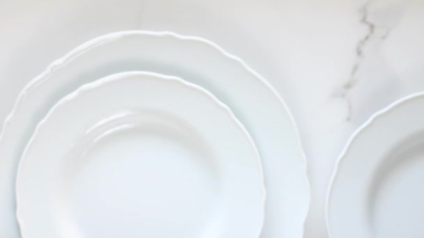 Piatti vuoti in porcellana bianca su tavolo in marmo, posate piatte con decorazioni a tavola, videografia cibo vista dall'alto come ispirazione per cucinare vlog o menu flatlay
 - Filmati, video