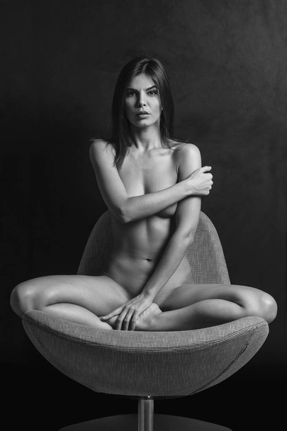 Beautiful nude woman sitting on a chair - 写真・画像