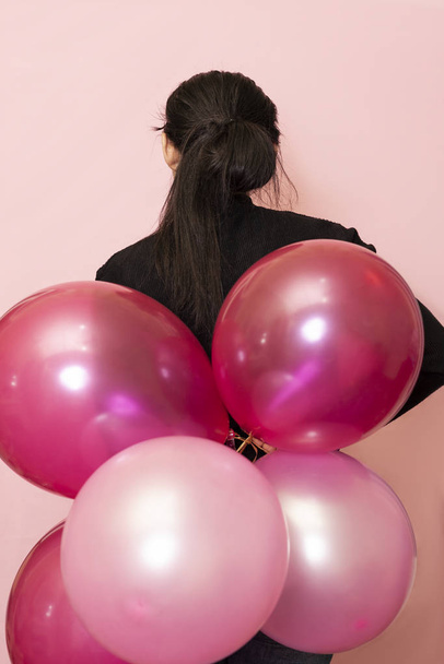 Mladá hezká žena v neformálním oblečení drží slavnostní vzduchové balónky. Portrét šťastné dvacítky středovýchodní feny oslavující Valentýna, narozeniny, párty - Fotografie, Obrázek