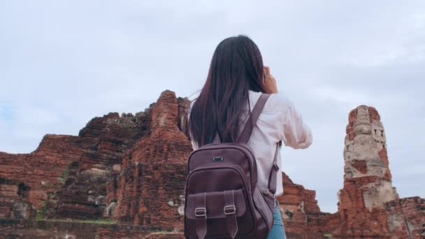 Reiziger Aziatische vrouw op vakantie in Ayutthaya, Thailand, Japanse backpacker vrouw genieten van haar reis op een geweldig oriëntatiepunt in de traditionele stad. Lifestyle vrouwen reizen vakantie concept. - Video