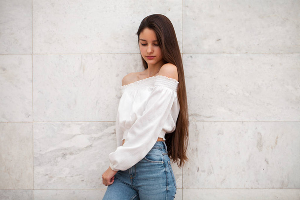 Young beautiful girl on a background of a white marble wall - Fotografie, Obrázek