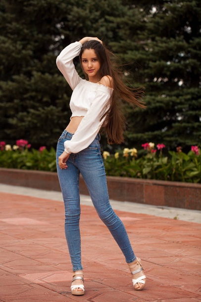 Pretty stylish brunette girl in blue jeans and white blouse  - 写真・画像
