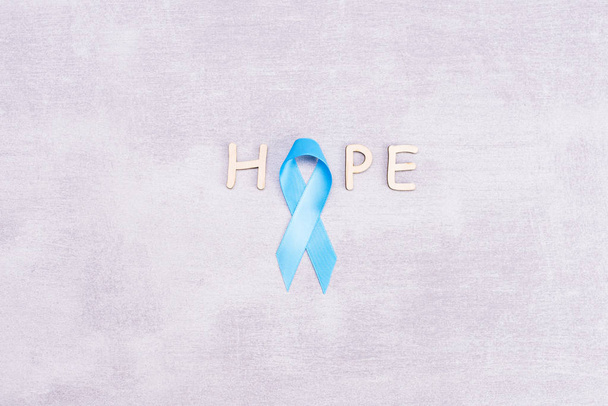 Healthcare and medicine concept - blue prostate cancer awareness ribbon and word hope made of wooden letters, achalasia and adrenocortical cancer, on gray background, flat lay, top view, flat lay, top - Фото, зображення