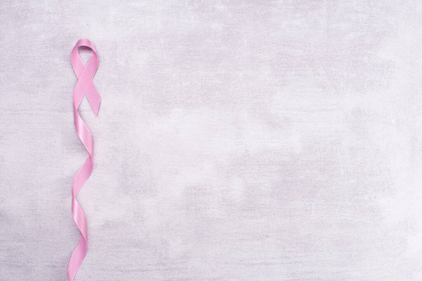 Healthcare and medicine concept - pink breast cancer awareness ribbon on gray background, flat lay, top view - 写真・画像