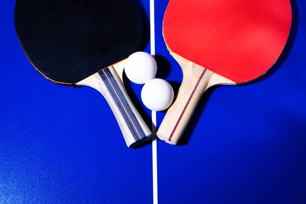 Raquetas y pelotas para tenis de mesa sobre fondo azul con líneas blancas
 - Foto, imagen