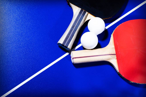 Raquetas y pelotas para tenis de mesa sobre fondo azul con líneas blancas
 - Foto, Imagen