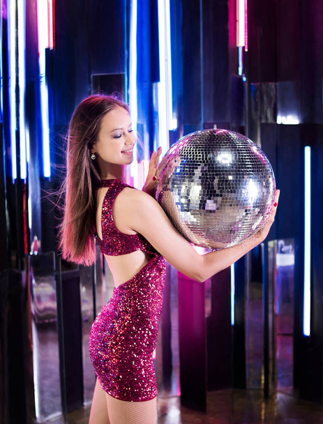 Привлекательная девушка с зеркальным дискотечным мячом в ночном клубе
 - Фото, изображение