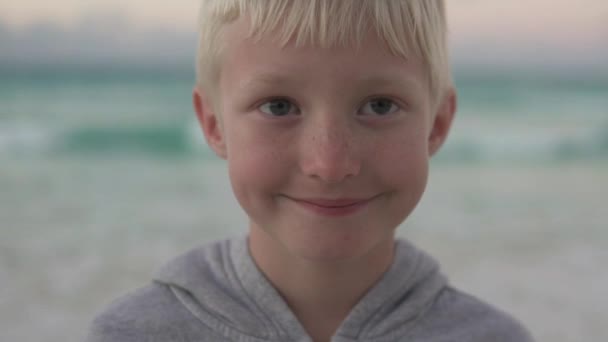 Close-up van een mooie blonde jongen met sproeten tegen de oceaan - Video