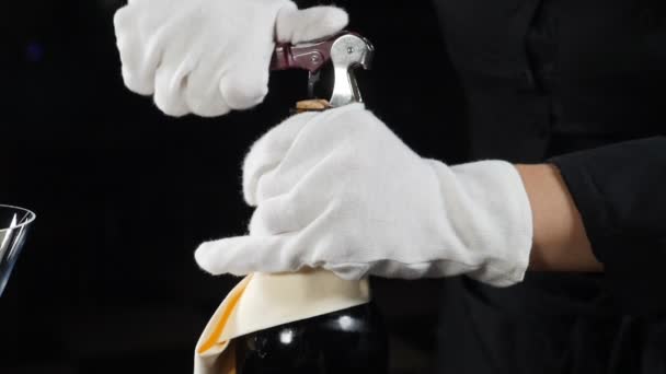Weingut-Konzept. Nahaufnahme des Sommeliers, der eine Flasche Wein für Besucher im Restaurant öffnet. Kellner in weißen Handschuhen auf schwarzem Rücken erschossen. . Zeitlupe. Voll hd - Filmmaterial, Video