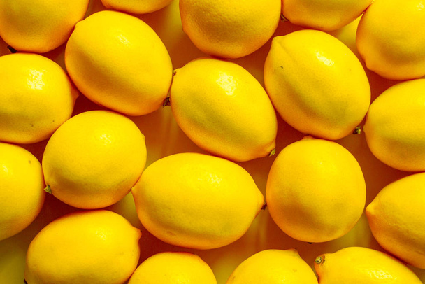 黄色の表面、背景または概念上の多くの熟したレモンを上から見る - 写真・画像