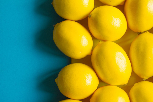 青い表面、背景、または概念上の多くの熟したレモンを上から見る - 写真・画像