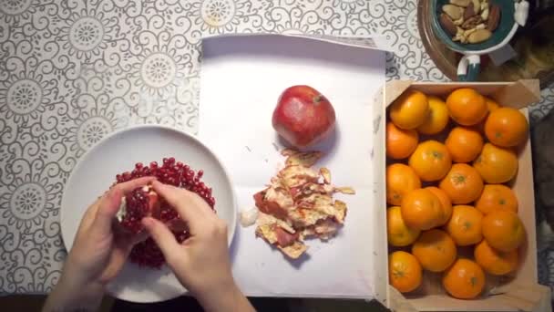 girl hands are cleaning pomegranate in a plate on the table - Кадры, видео