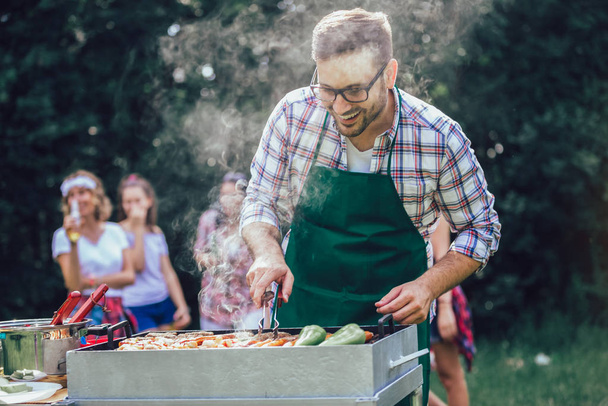 Handsome male preparing barbecue outdoors for friends - Photo, Image
