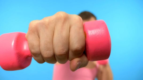 Playful handsome man in a pink t-shirt is engaged in fitness in pink glasses with pink dumbbells. Bright Fitness. Sports Fashion Accessories - Photo, image