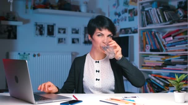 Büroangestellte am Tisch trinkt Wasser, nutzt Smartphone - Filmmaterial, Video