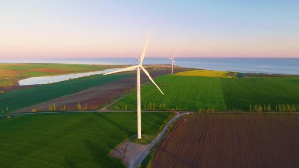 Farma turbin wiatrowych na pięknym, wieczornym krajobrazie. Produkcja energii odnawialnej dla ekologicznego świata. Widok z powietrza na park farmy wiatraków wieczorem - Materiał filmowy, wideo