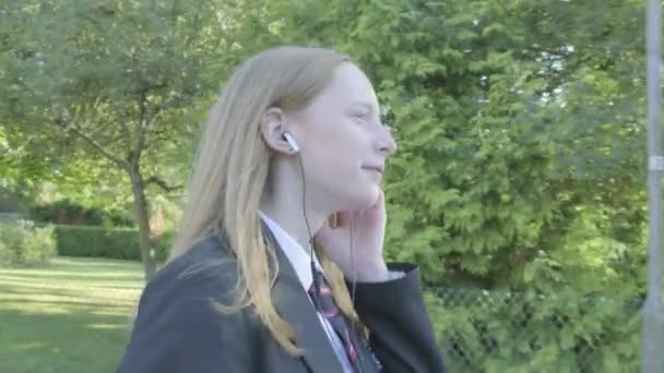 Senior school girl walking to school listening to music themes of music technology routines education - Footage, Video