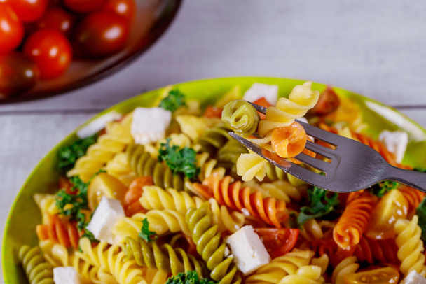 Italiaanse kleurrijke pasta rotini met kerstomaten op witte houten achtergrond. - Foto, afbeelding