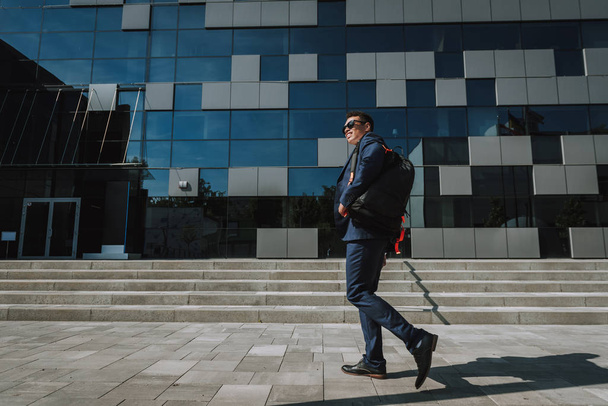 Grinning employee going to work with backpack stock photo - 写真・画像