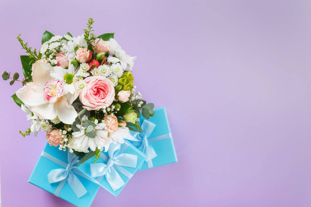Top view flower bouquet on purple background with gift boxes copy space flat lay - Photo, Image