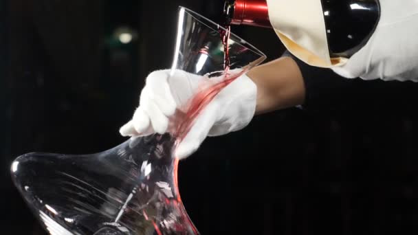 Viini ja viinitila käsite. Punaviini kaadetaan viinindekantterissa tummalla pohjalla. Lähikuva punaviinipullon kaulasta kaatamalla dekantteriin. hidastettuna. Viininpoisto. Täysi hd
 - Materiaali, video