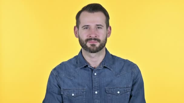 Jóképű szakállas fiatalember mutató ujját és meghívó, sárga háttér - Felvétel, videó