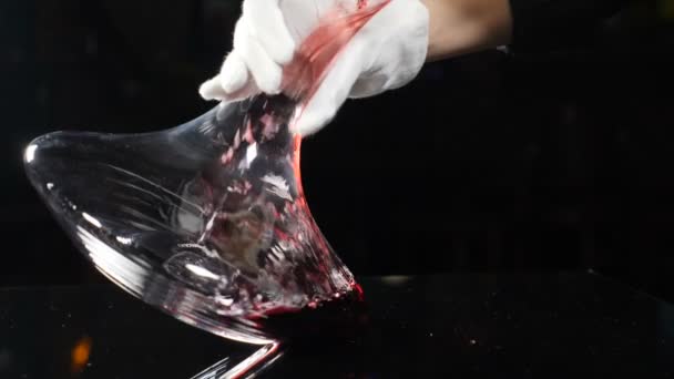 スローモーションで赤ワインをデカンタに注ぐソムリエのクローズアップ。レストランでのワインの劣化プロセス,黒の背景にエレガントな白い手袋で手.スローモーション。フルHD - 映像、動画