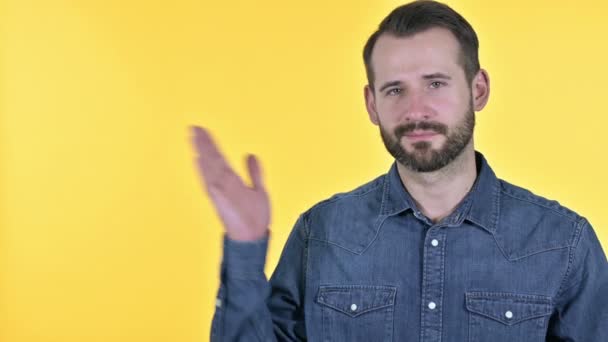 手に製品を保持髭の若い男,黄色の背景 - 映像、動画