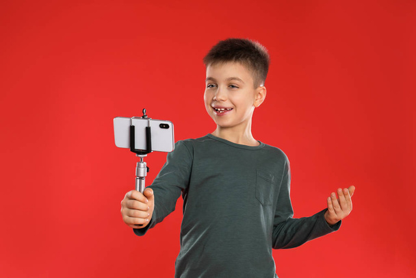 Cute little blogger recording video on red background - Photo, image