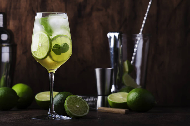 Mojito cocktail with lime and mint in wine glass on wooden background. Copy space - Foto, Imagem