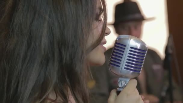 Портрет молодой красавицы латиноамериканской брюнетки, поющей с ретро-микрофоном, на зеленом фоне - Кадры, видео