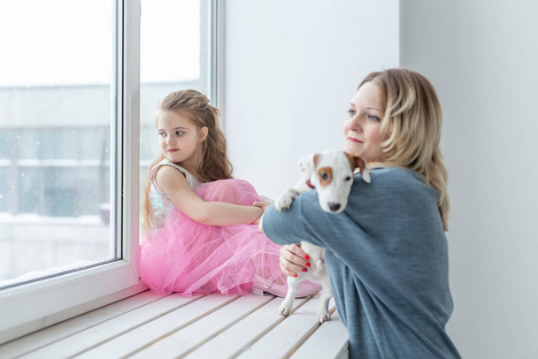 Familia y concepto de mascota - madre e hija jugando con Jack Russell terrier perro en casa
 - Foto, imagen