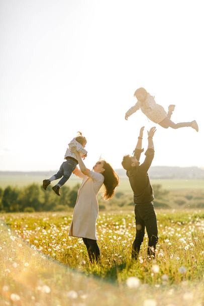 happy family walks in nature. Mom and Dad throw their children - Фото, изображение