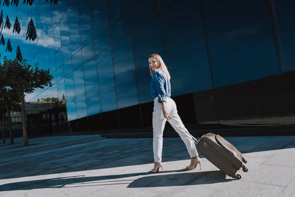 Beautiful stylish lady carrying travel suitcase and smiling - Фото, изображение