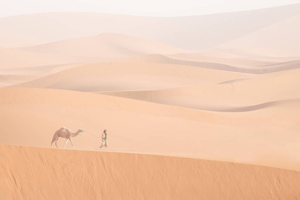 Бедуїн і верблюд їдуть через піщані дюни. Чудовий захід сонця з караваном у пустелі Сахара (Марокко, Африка).. - Фото, зображення