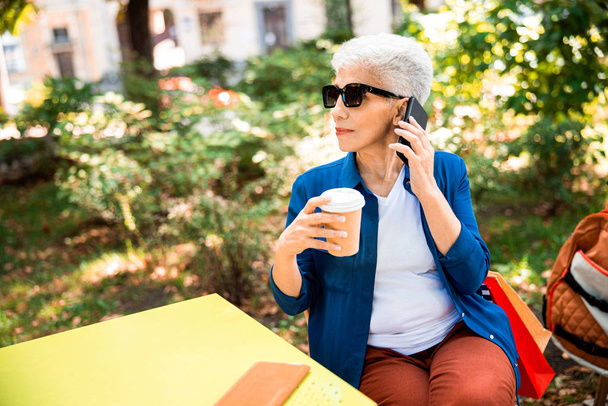 Elegant mature lady talking on cellphone on the street - Foto, immagini
