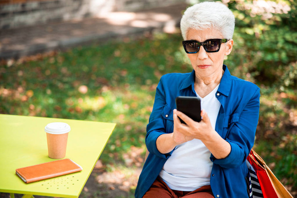 Elegant senior lady using smartphone on the street - Valokuva, kuva