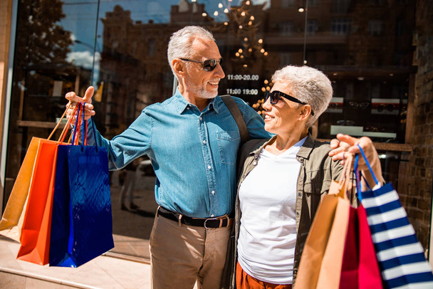 Cheerful senior couple with purchases standing on the street - Foto, afbeelding