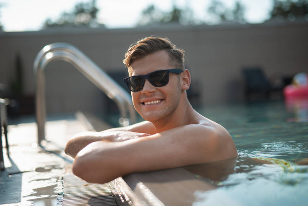 Iloinen nuori mies rentouttava uima-altaassa
 - Valokuva, kuva