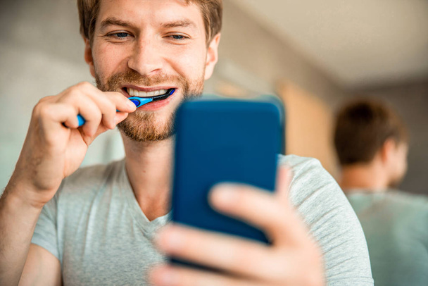 Bearded young man brushing teeth and making selfie - Photo, Image