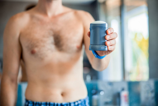Young man with naked torso holding antiperspirant - Fotoğraf, Görsel