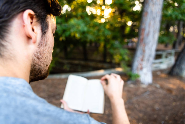 Un homme lit un roman détendu assis dans un parc au coucher du soleil, amant o
 - Photo, image