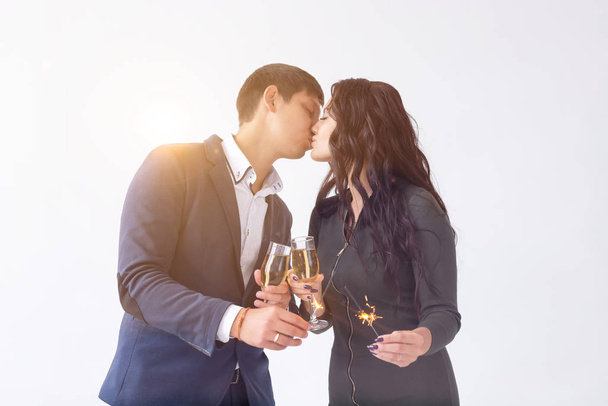 Concepto de día y fecha de San Valentín - Pareja con copas de champán y bengalas sobre fondo blanco
 - Foto, Imagen