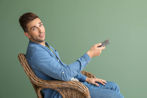 Bello uomo guardando la TV mentre seduto in poltrona su sfondo di colore
 - Foto, immagini