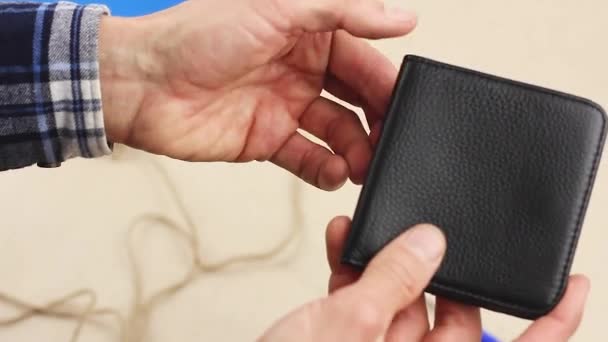 human hand puts blue paper heart into black leather wallet, concept of valentine gift surprise or good investment or lucky talisman, close-up   - Filmati, video
