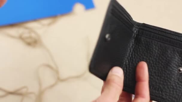 human hand puts blue paper heart into black leather wallet, concept of valentine gift or lucky talisman, close-up   - Footage, Video