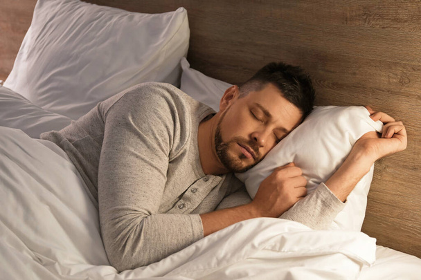 Handsome man sleeping in bed at night - Photo, Image