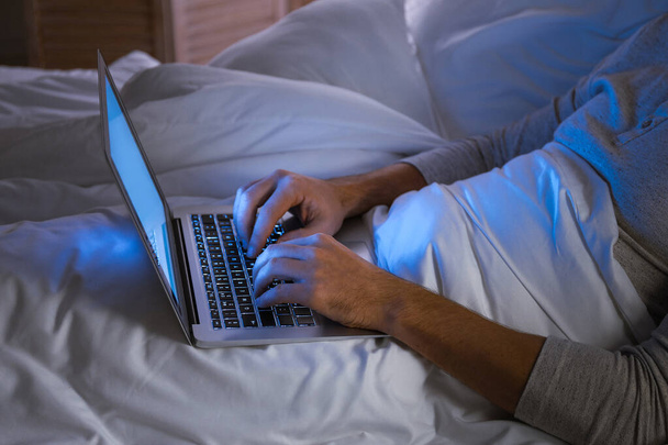 Человек с ноутбуком в постели ночью
 - Фото, изображение