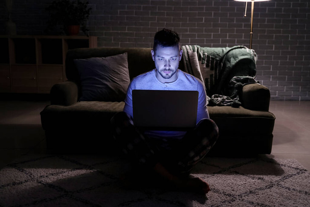 Uomo con computer portatile a tarda sera a casa
 - Foto, immagini