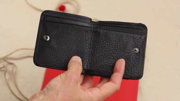 human hand puts red paper heart into black leather wallet, concept of valentine gift surprise or good investment or lucky talisman, close-up   - Footage, Video